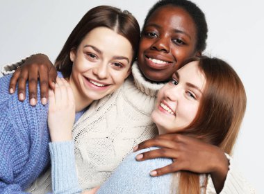 Portrait of charming multiracial female friends over light grey background. Lifestyle, friendship and people concept.