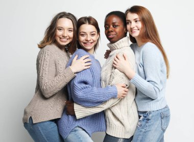 Portrait of charming multiracial female friends over light grey background. Lifestyle, friendship and people concept.