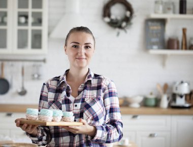 Young baker woman holding marshmallow. Happy, smiling and cheerful. Freelance, food and hobby concept.