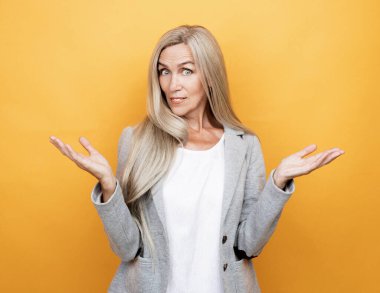 lifestyle, emotion and people concept: old nice beautiful surprised woman with ling hair. Isolated over yellow color background.