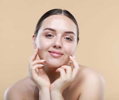 Yanaklarını tutarak gülen mutlu güzel bir kadın. Temiz tenli genç bir bayan. Güzellik yüz bakımı ve tedavi. Etkileyici yüz ifadeleri. Kozmetik ve kaplıca kavramı.