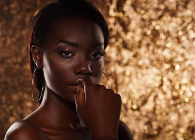 Beauty portrait of a sensual African woman over gold background. Close up.