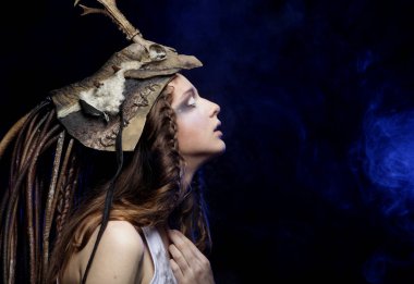 Parlak makyajlı, örgülü saçlı ve kafasında siyah bir arka planda poz veren güzel bir genç kadın. Karnaval partisi, Cadılar Bayramı konsepti.