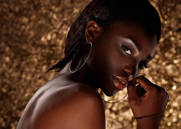 Close-up of a beautiful black woman with fashion make-up. Glamorous portrait over gold background.