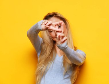 lifestyle, emotion and young people concept: Young blonde woman smiling and show v-sign over yellow background