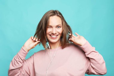 lifestyle, emotion and young people concept: charming smiling young woman dressed pink sweater over blue background
