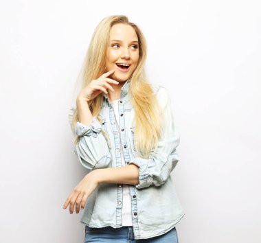 charming young woman with long blond hair wearing casual denim shirt smiling over white background