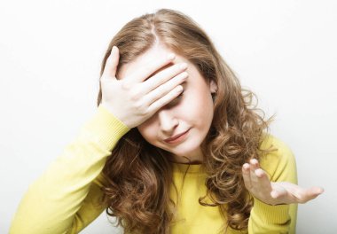 Young woman clutching her head with her palms while suffering from a migraine. Portrait over white background.