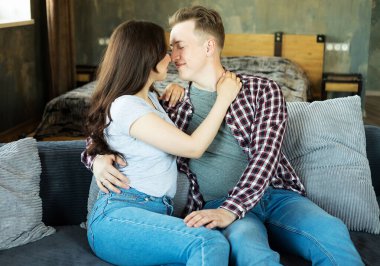 Young beautiful couple is sitting on the couch and hugging. Happy family life. Love.