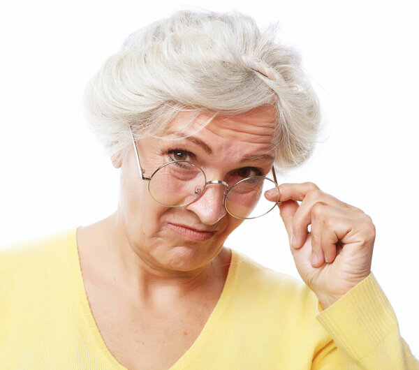 An elderly woman looks skeptically over her glasses. Portrait over white background.