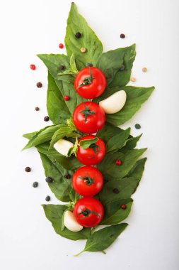 Beyaz arka planda fesleğen, biber ve sarımsaklı olgun kırmızı domatesler. Üst Manzara. Vejetaryen yemeği..