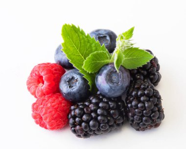 Yaprakla böğürtlen karıştır. Beyaz arka planda izole edilmiş çeşitli taze meyveler. Ahududu, yabanmersini, kızılcık, böğürtlen ve nane yaprakları