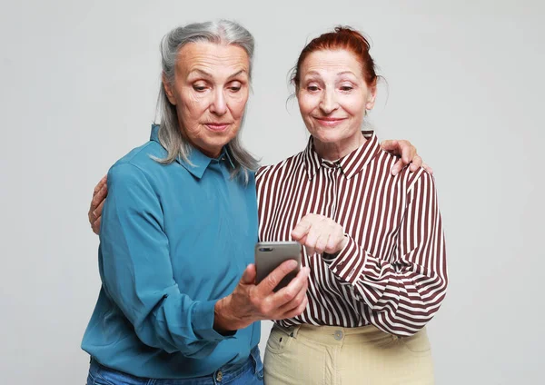 Δύο Ηλικιωμένες Ηλικιωμένες Γυναίκες Κοιτούν Τηλέφωνο Και Διαβάζουν Τις Ειδήσεις — Φωτογραφία Αρχείου