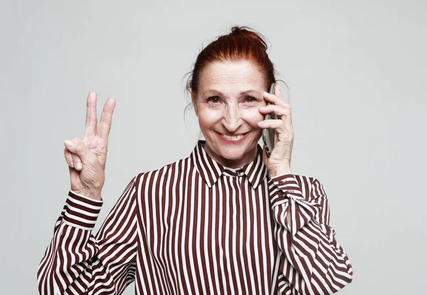 Alte Lächelnde Frau Gestreiftem Hemd Spricht Auf Handy Und Zeigt — Stockfoto