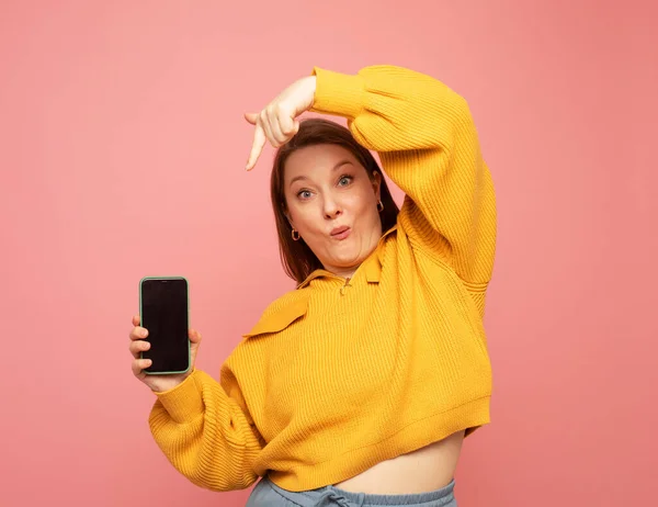 Smiling Adult Woman Wearing Yellow Sweater Showing Presenting Mobile Phone — Stock Photo, Image