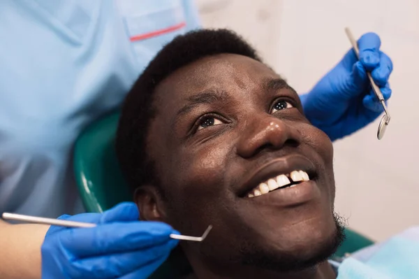 Portrait of black male patient getting teeth treatment with dentist at modern clinic. People, medicine, stomatology, technology and health care concept.