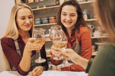 Üç neşeli genç bayan arkadaş seramik bir atölyede eğleniyorlar. Şarap içip şakalaşıyorlar, eğleniyorlar. Yaşam tarzı kavramı.