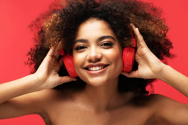 stock image People, music, emotions concept. Young afro american female with dances in rhythm of melody. Portrait over red color background.