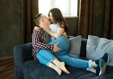 Young beautiful couple is sitting on the couch and hugging. Happy family life. Love.