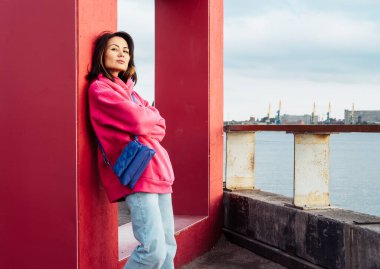 Beautiful stylish Asian young woman in pink sweatshirt, outdoor portrait, summer time.