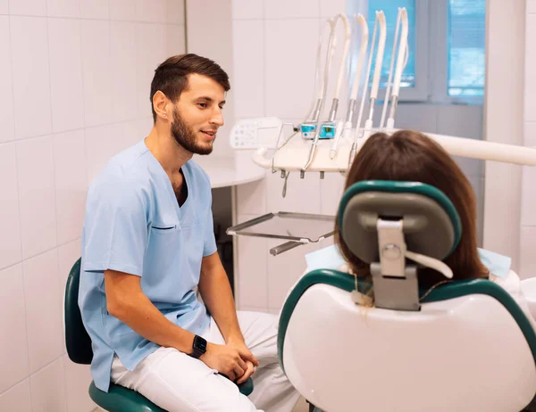 牙医在牙科诊所检查牙齿时 与年轻女子交流 — 图库照片