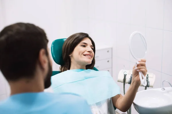 Gülümseyen Kadın Hasta Dişçi Muayenehanesinde Oturan Güzel Gülüşüne Bakıyor — Stok fotoğraf