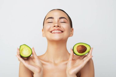 Hafif arka planda taze avokadosu olan güzel genç bir kadın. Yüksek kalite fotoğraf. Portreyi kapat.