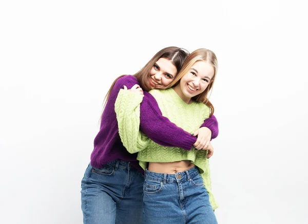 Δύο Χαρούμενες Νεαρές Γυναίκες Αγκαλιάζονται Και Διασκεδάζουν Μαζί Λευκό Φόντο — Φωτογραφία Αρχείου
