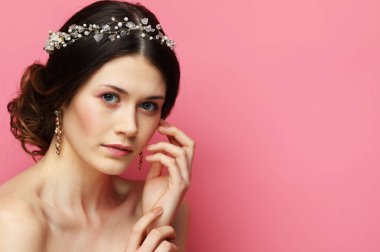 Beautiful young bride with fashion wedding hairstyle. Portrait of young woman over pink background.