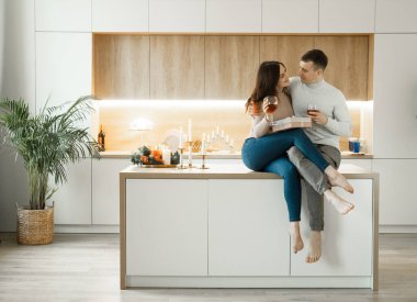Genç aşık çift mutfakta kırmızı şarap içiyor. Rahat bir ev. Aşk ve romantik. Yaşam biçimi.