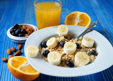 Sağlıklı kahvaltı, yemek ve diyet konsepti - muzlu yulaf ezmesi, portakal suyu ve sütle birlikte beyaz tabakta taze böğürtlen, kapat