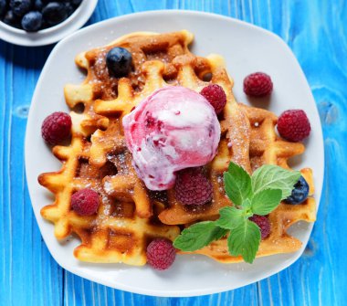 Kahvaltı için dondurmalı waffle ve ahududu mavi ahşap masada. Kapat..