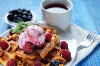 Kahvaltı için dondurmalı waffle ve ahududu mavi ahşap masada. Kapat..