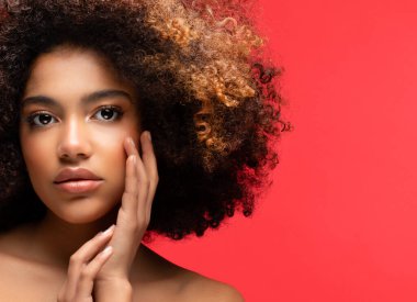 Kırmızı arka planda güzel makyajlı genç Afrikalı modelin portresi