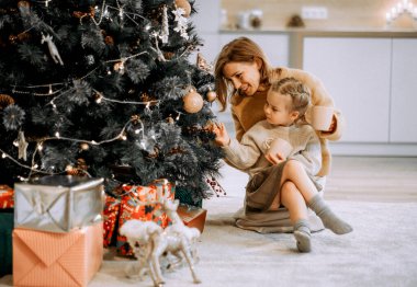 Aile, kış tatili ve insanlar konsepti. Mutlu anne ve küçük kız evde Noel ağacı süslüyorlar..