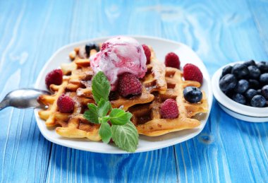 Kahvaltı için dondurmalı waffle ve ahududu mavi ahşap masada. Kapat..