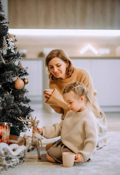 Aile, kış tatili ve insanlar konsepti. Mutlu anne ve küçük kız evde Noel ağacı süslüyorlar..