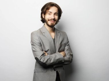 Sakallı ve bıyıklı, şık giyinmiş yakışıklı bir erkek model. Gri arkaplanda bir portre.