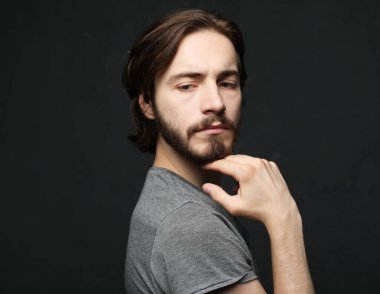 Sakallı ve bıyıklı, şık giyinmiş yakışıklı bir erkek model. Gri arkaplanda bir portre.