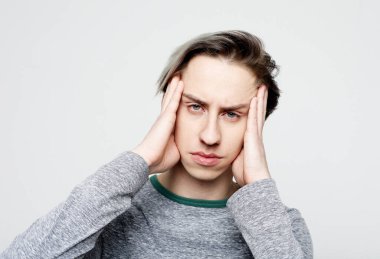 Stresli genç adam acı çekiyor şiddetli baş ağrısı konsepti var, yorgun üzgün adam migrenden muzdarip şakaklara masaj yapıyor beyaz gri stüdyo boş arka planda izole edilmiş
