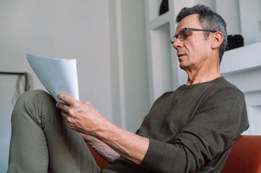 Gri saçlı, sıradan giyinmiş yaşlı bir adam kanepeye oturur ve defterine çizimler yapar. Yaratıcılık, yaşam tarzı ve insanlar kokuşmuş.