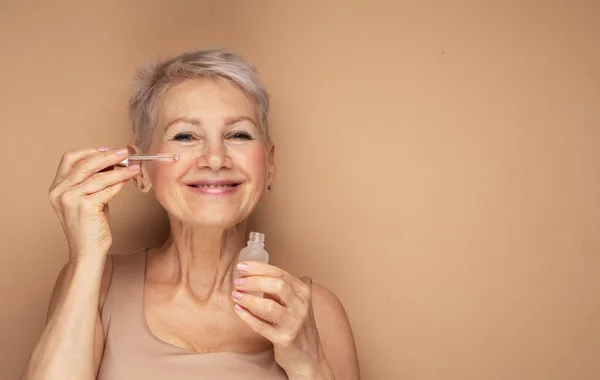 Happy Senior Lady Applies Cosmetic Oil Serum Face Takes Care — Stock Photo, Image