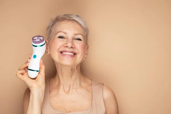 Beautiful 60S Woman Holding Massager Her Hand Beige Background Spa — Stock Photo, Image