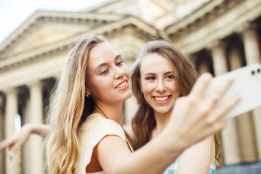Şehirde selfie çeken iki mutlu genç kadın. Yaz günü. Arkadaşlık kavramı.