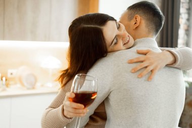 Genç aşık çift mutfakta kırmızı şarap içiyor. Rahat bir ev. Aşk ve romantik.
