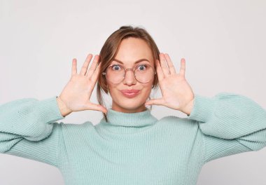 Çekici sarışın kadın gülüyor ve hayattan zevk alıyor. Gri arka planda sıradan giyinmiş bir kız..