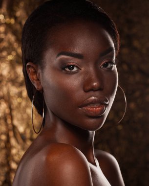 Beauty portrait of a sensual African woman over gold background. Close up.
