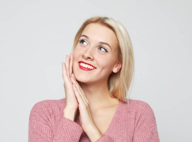 Gri arka planda izole edilmiş güzel sarışın bir kadının stüdyo fotoğrafı..