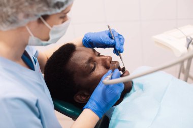 Modern klinikte diş tedavisi gören genç zenci bir hastanın portresi.