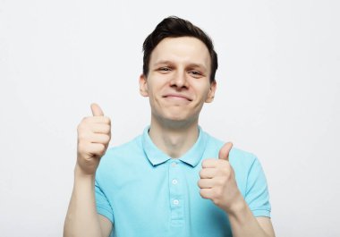 Beyaz arka planda tamam işareti gösteren genç yakışıklı adam.